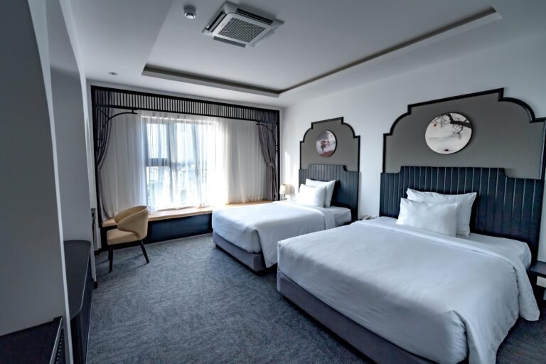 Spacious hotel room featuring two twin beds, elegant decor, and stylish furnishings.