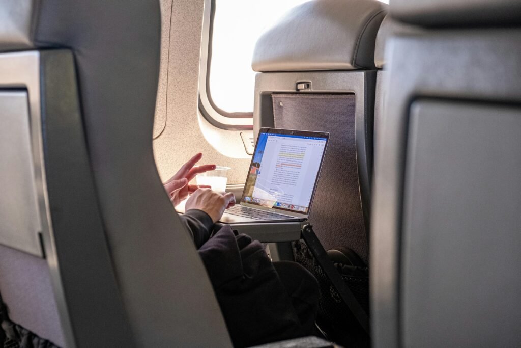 Passenger working on a laptop during flight, highlighting travel productivity.