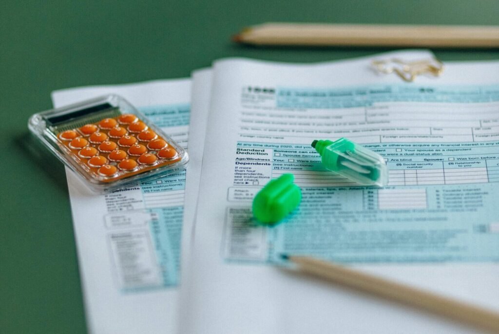 Close-up of tax documents with calculator on a green table, ideal for finance themes.